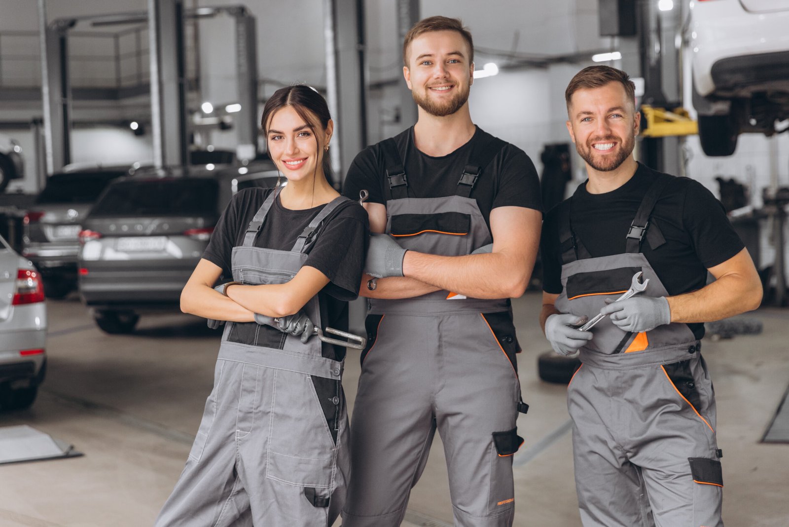 Group of three car service technician men and woman talking at w